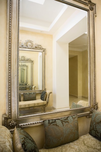 Detail of a large wall mirror over a loveseat with decorative pillows