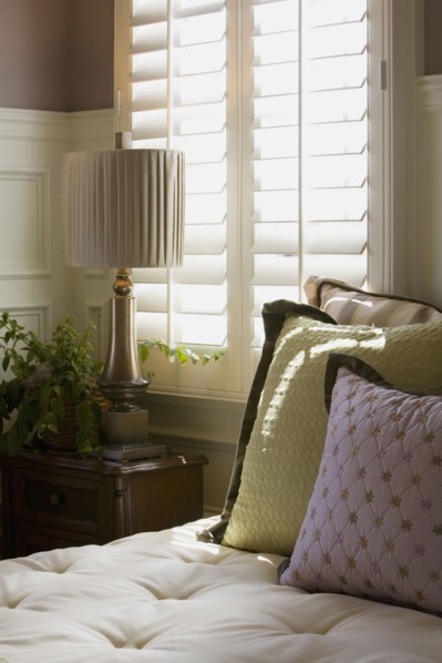 Purple and green decorative pillows on bed near window