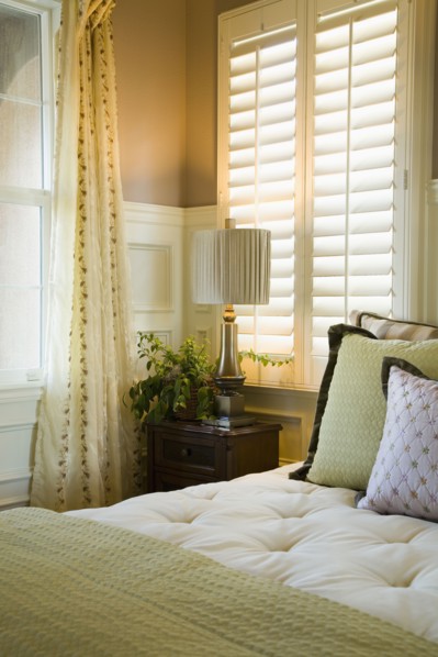 Purple and green decorative pillows on bed near window