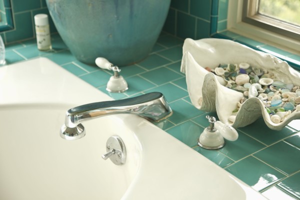 Decorative shells on aqua tile bathroom counter near sink
