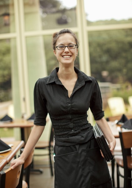 Portrait of smiling Hispanic waitress holding menus in restaurant