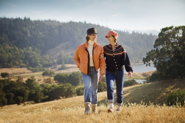 Women walking arm in arm near field