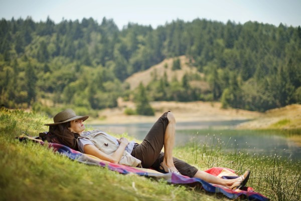 Hispanic woman relaxing on blanket near river