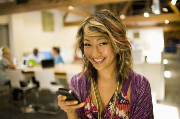 Japanese businesswoman using cell phone in communal workspace