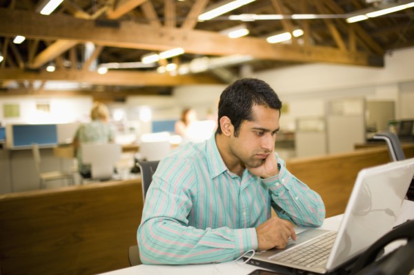 Pacific Islander businessman using laptop in communal workspace