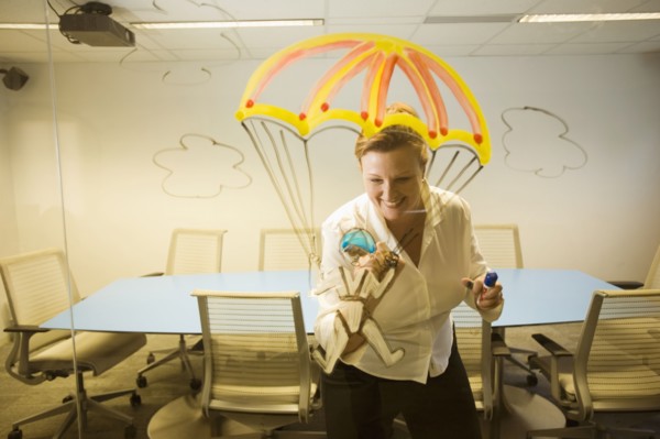 Caucasian businesswoman drawing a golden parachute on conference room wall