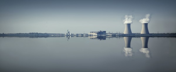 Smoke stacks and factory reflected in still lake