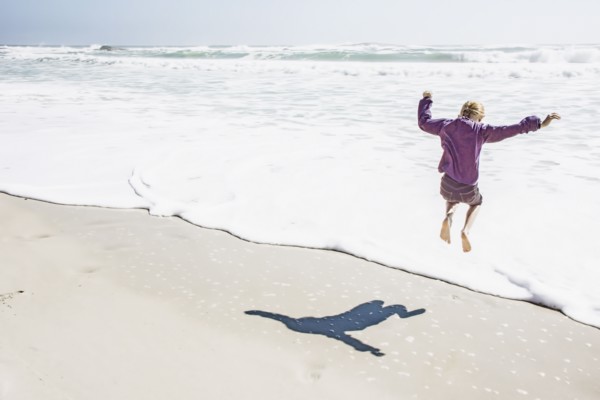 Girl playing in waves on sunny beach