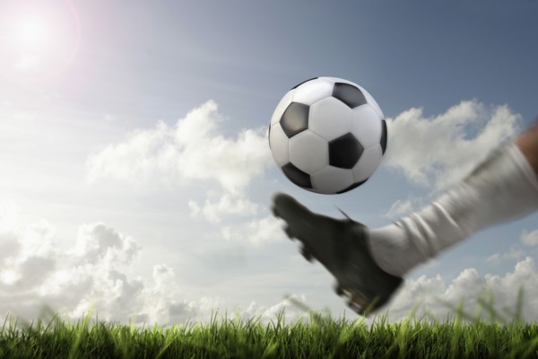Blurred view of foot kicking soccer ball