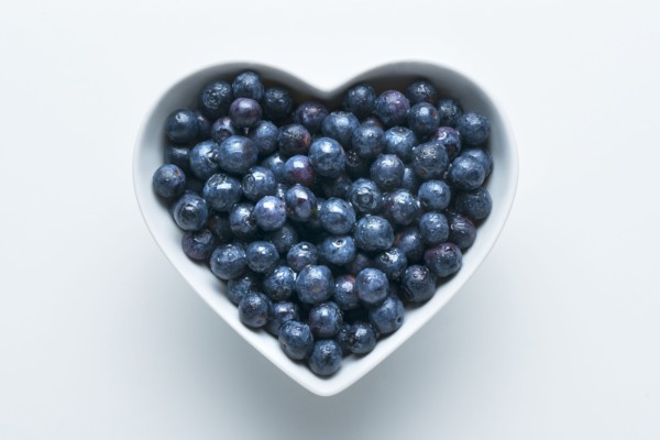 Blueberries in heart-shape bowl on white background