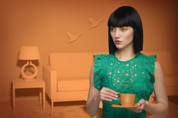 Caucasian woman in orange old-fashioned livingroom drinking coffee
