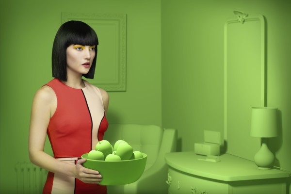 Caucasian woman in green old-fashioned bedroom carrying bowl of apples