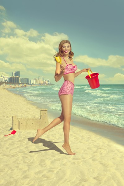 Caucasian woman running on beach carrying shovel and pail