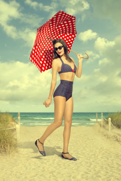 Caucasian woman holding polka-dot umbrella at beach