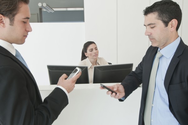 Hispanic businessmen holding cell phones in office