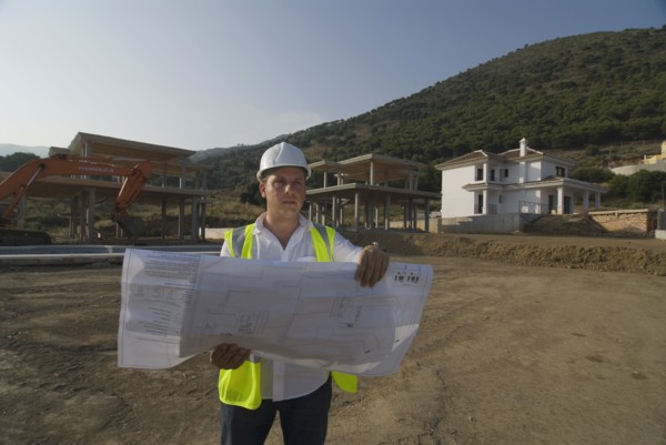 Male engineer wearing hard hat looking at plans on building site
