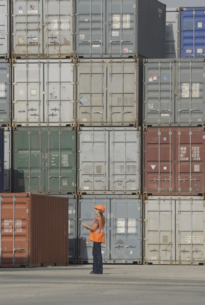 Female worker with clipboard in cargo container terminal low angle