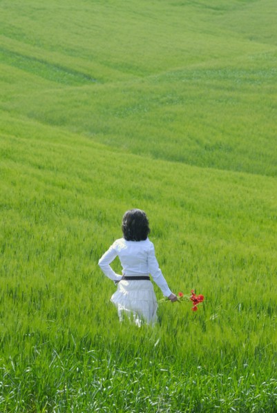 Woman standing in field rear view