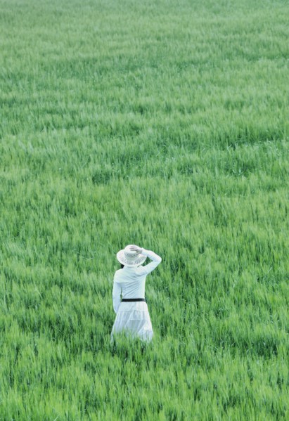 Woman wearing hat standing in field rear view