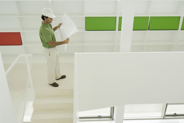 Male architect looking at plan in recently finished office building