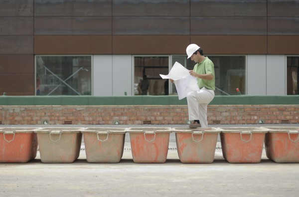 Engineer studying plan on construction site smiling profile