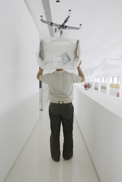 Man carrying chair thorugh office rear view