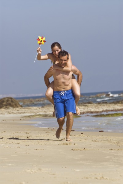 Man carrying woman on shoulders on beach