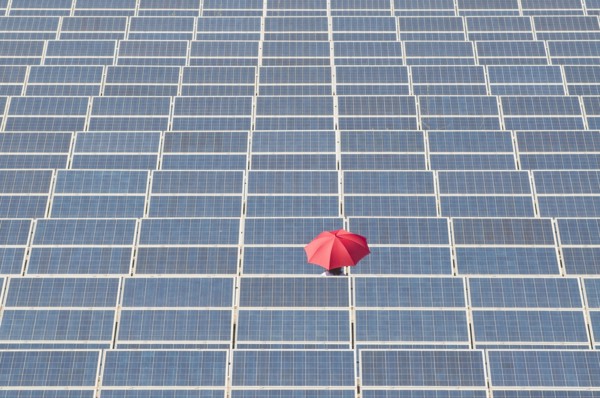 woman holding red umbrella in solar plant
