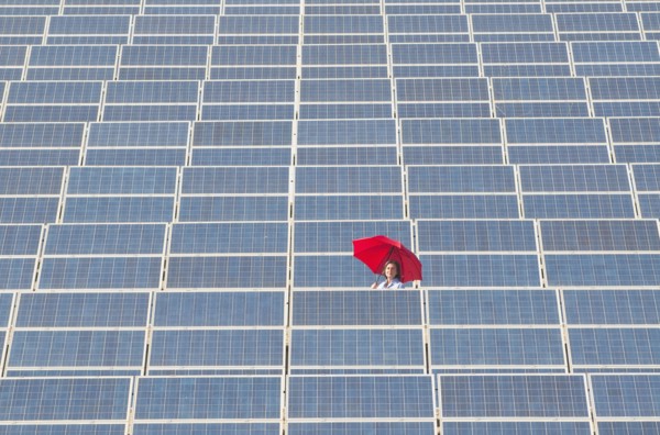 woman holding red umbrella in solar power plant