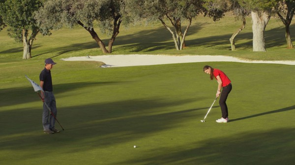 Caucasian couple putting on golf course