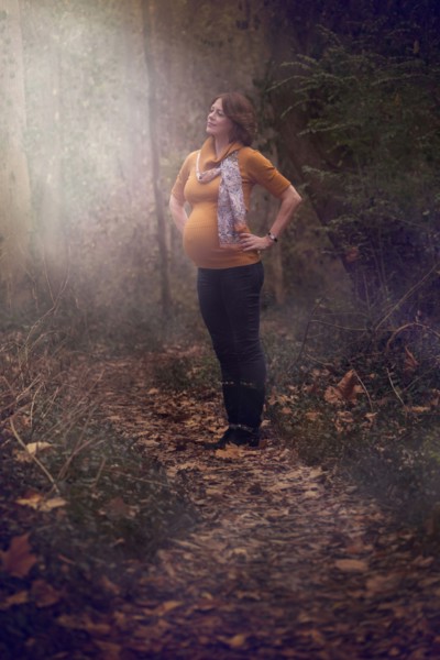Pregnant Caucasian woman standing in forest