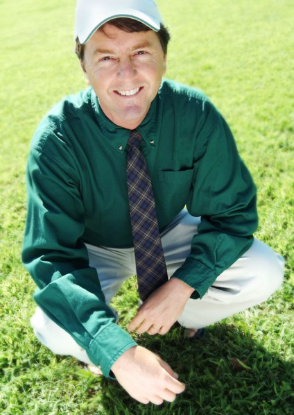 Businessman crouching on grass lawn