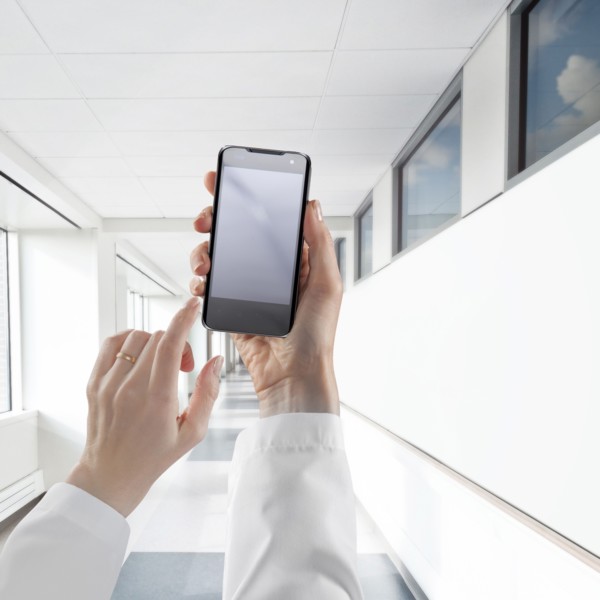 Businesswoman using cell phone in white corridor