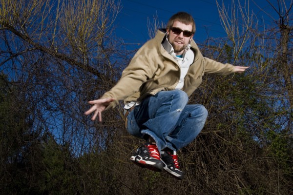 Man wearing sunglasses jumping for joy in forest