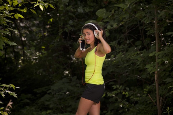 Hispanic woman holding headphone and cell phone in forest