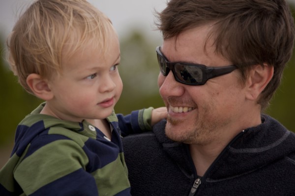 Caucasian father wearing sunglasses holding son