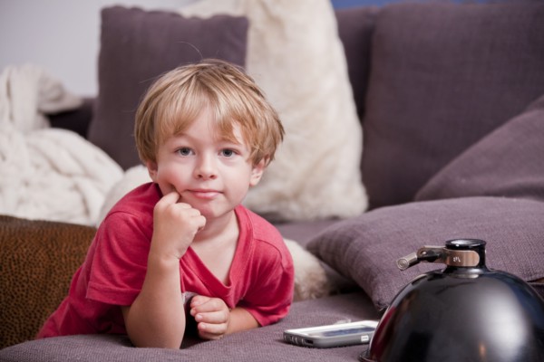 Caucasian boy leaning on sofa near cell phone