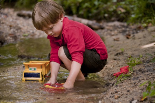 Caucasian boy playing with construction toys in river