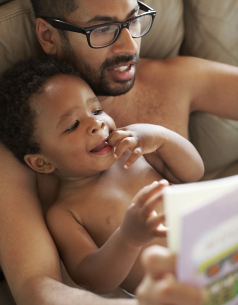 Father reading book to African American baby