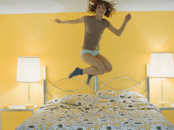 Woman jumping on bed