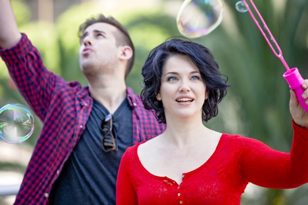 Caucasian couple blowing bubbles outdoors