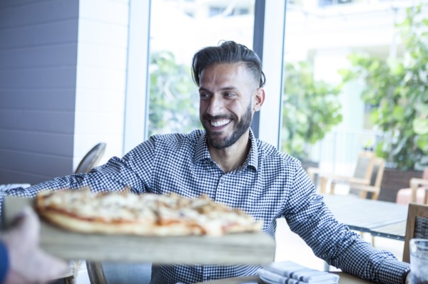 Server bringing diner pizza in restaurant