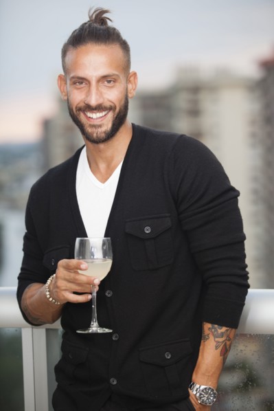 Hispanic man drinking wine on urban balcony