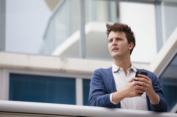 Caucasian businessman using cell phone on balcony