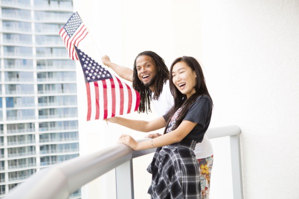 Couple waving American flags on urban balcony