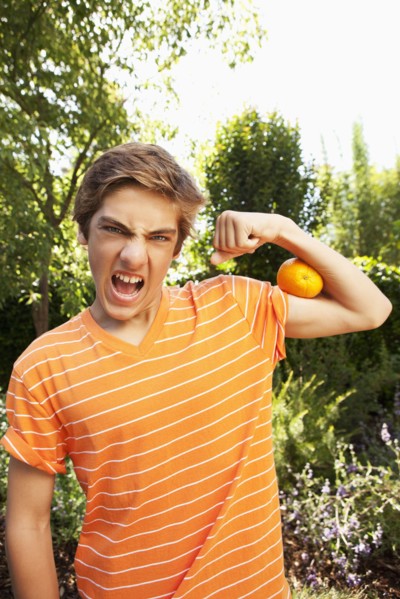 Caucasian teenager squeezing orange with arm