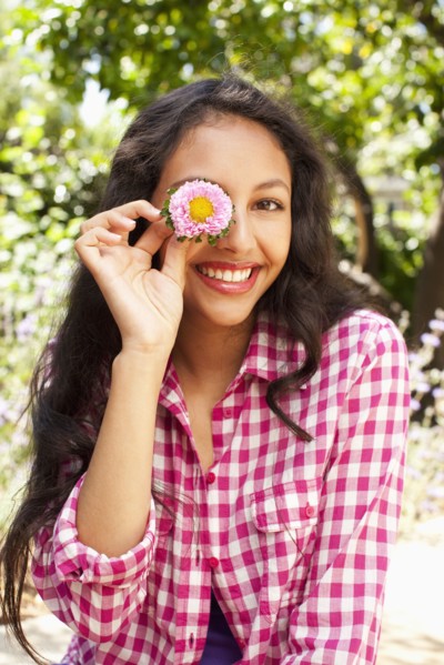 Mixed race teenager holding flower in front of her face