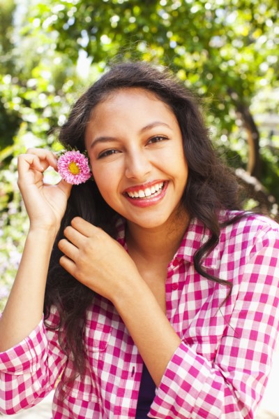 Mixed race teenager putting flower in hair