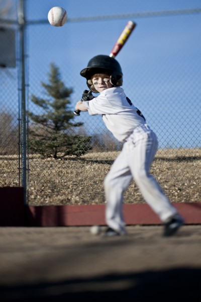 Caucasian boy hitting baseball on field