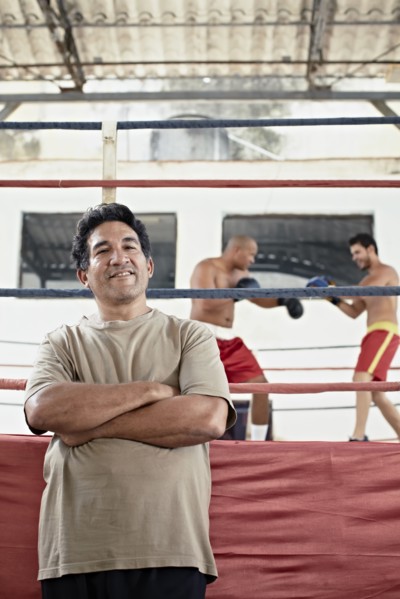 Hispanic trainer standing next to boxers fighting in ring